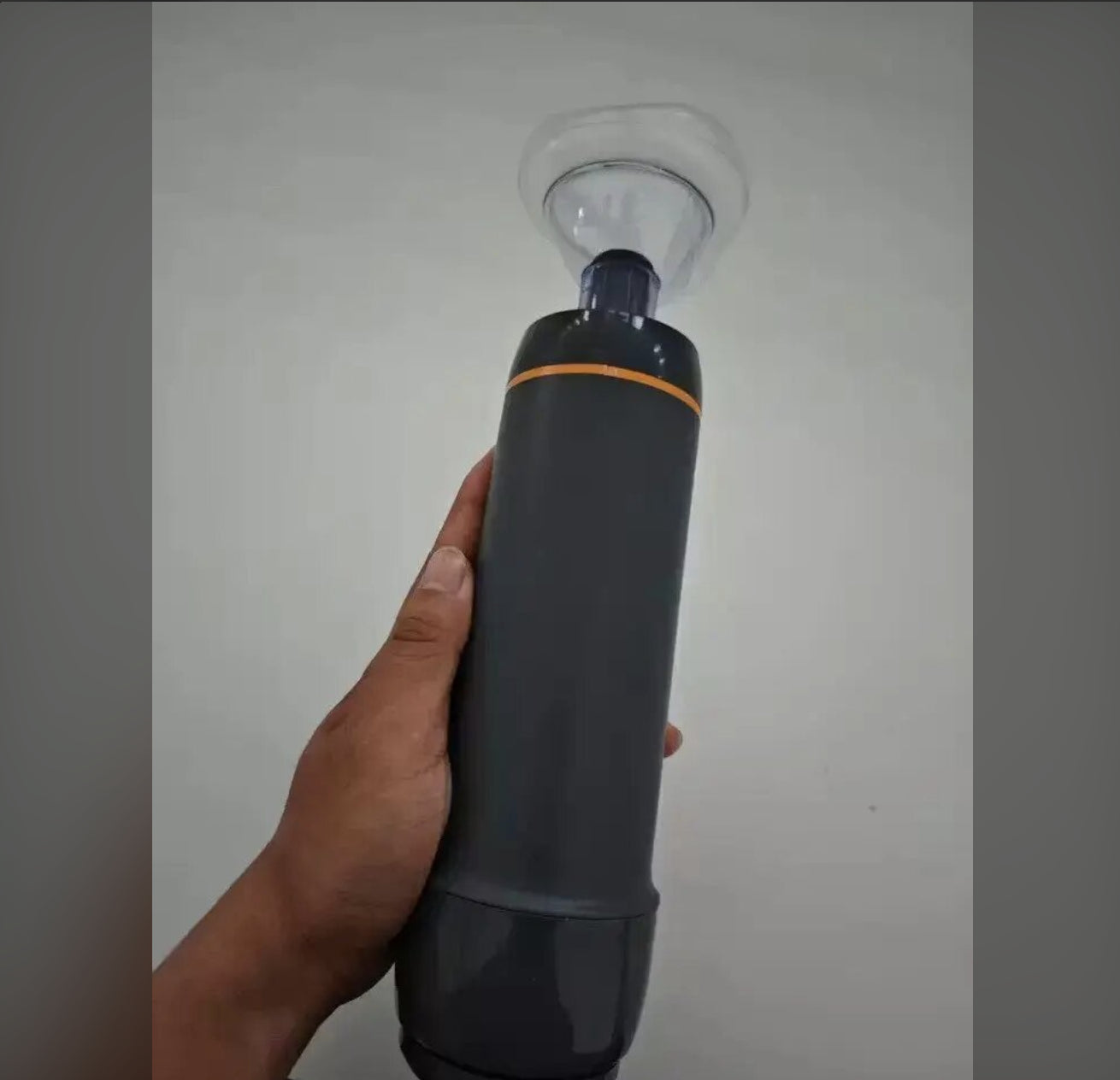A hand holds the charcoal suction device with its attached clear mask.