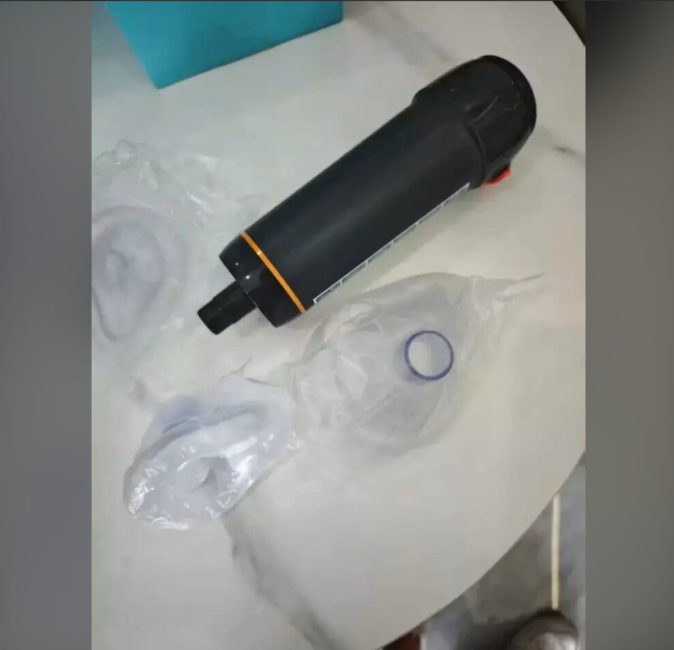 The device and separately wrapped clear masks rest on a light tabletop.